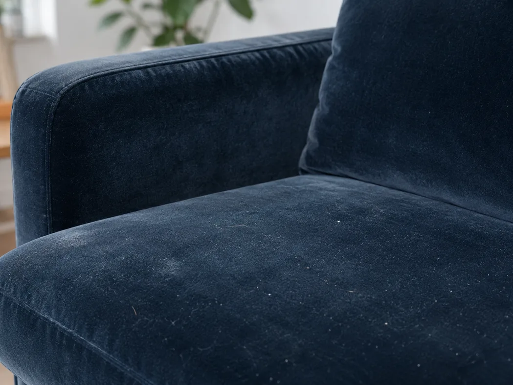 Dunkelgrünes Velours-Sofa im Detail — sichtbar langer, dichter Flor, der Hausstaub und Allergene tief in der Faser bindet