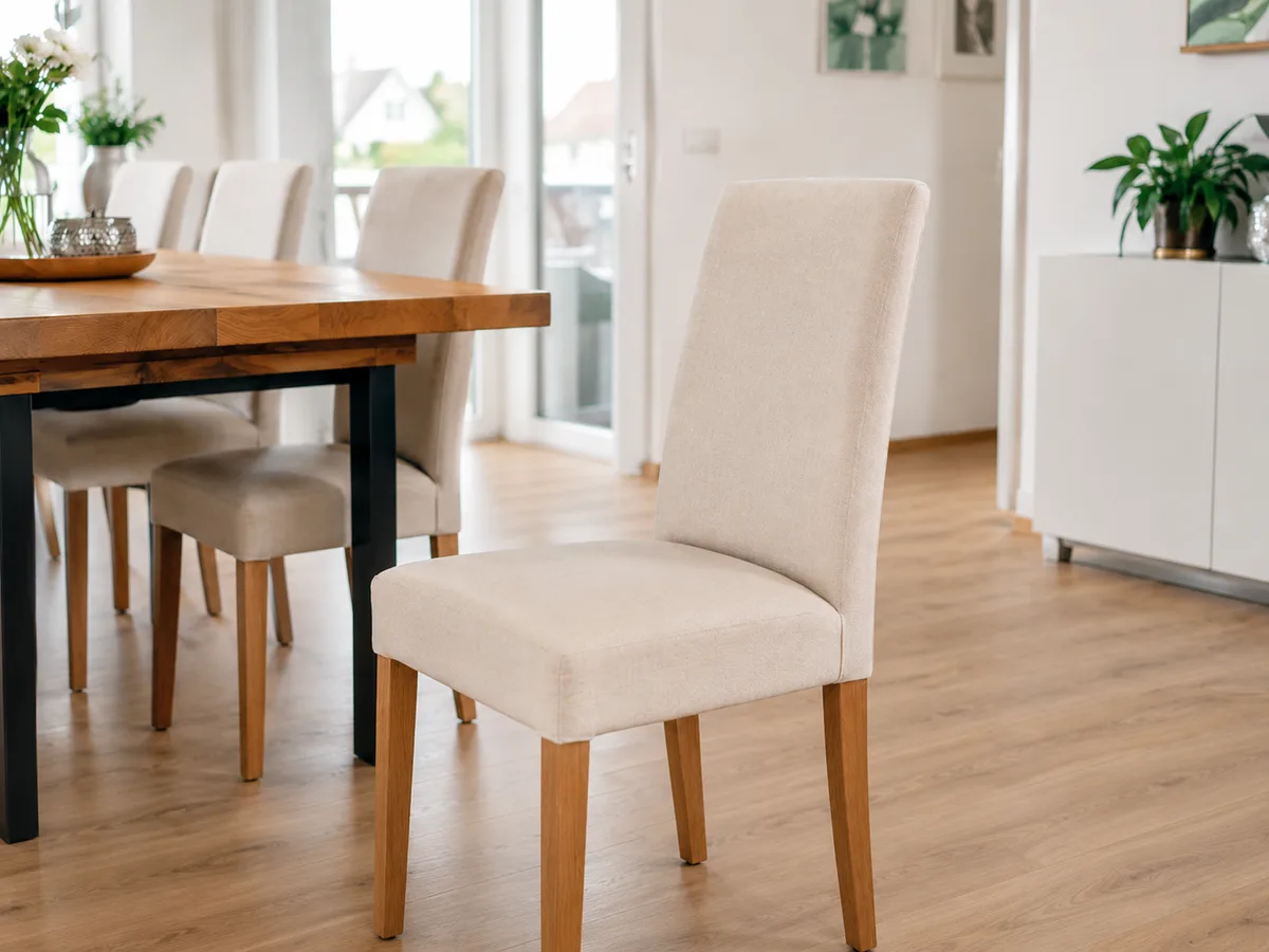 Vier weiße Esszimmerstühle um einen Holztisch in einem hellen Esszimmer — alle gleichmäßig sauber